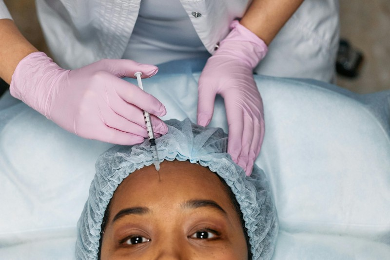 A woman getting Botox injection in her forehead.